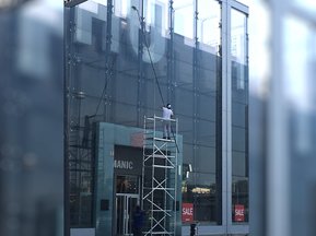 Mitarbeiter beim Reinigen einer Glasfassade mit Hebebühne